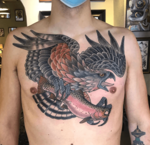 Big neotraditional eagle or hawk chest tattoo with a fish. 